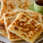 Traditional Arabic Breakfast Food Recipes: A Delicious Start to Your Day 9 Stack of golden brown Msammen (Moroccan square bread) on a white plate with a cup of green mint tea.