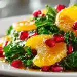 Citrus Pomegranate Kale Salad with Honey 11 Fresh citrus kale pomegranate salad with orange slices, kale leaves, and pomegranate seeds on a white plate.